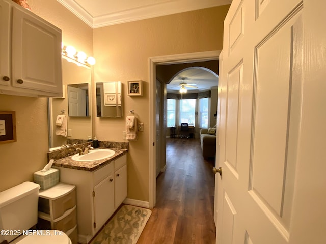 bathroom featuring vanity, wood finished floors, ceiling fan, ornamental molding, and toilet