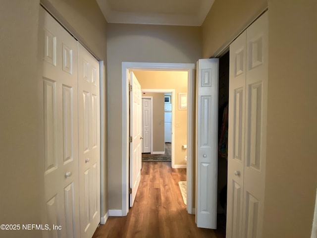 hallway featuring dark wood finished floors and baseboards