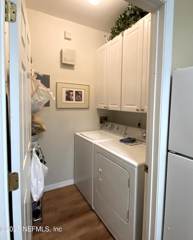 clothes washing area with wood finished floors, cabinet space, baseboards, and washer and clothes dryer