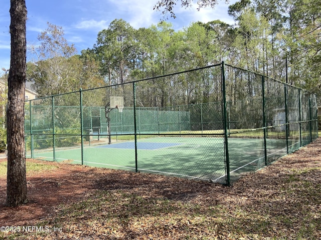 view of tennis court with community basketball court and fence