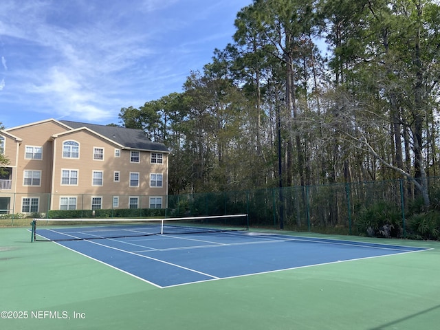 view of tennis court featuring community basketball court and fence