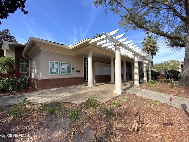 back of property with a pergola, brick siding, and stucco siding