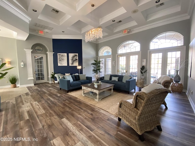 living room with a notable chandelier, wood finished floors, visible vents, and a towering ceiling