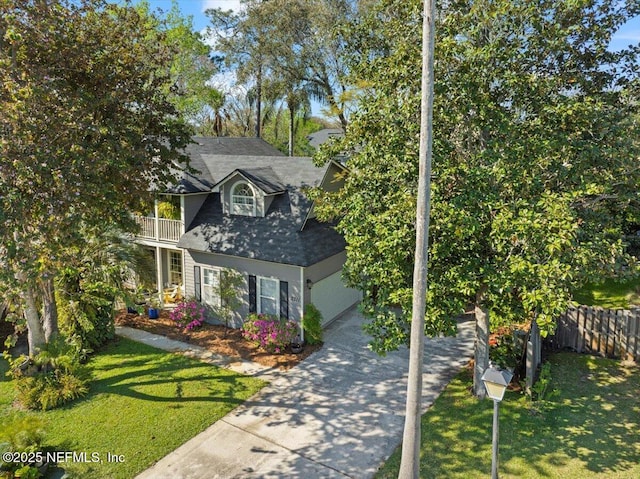 view of front facade featuring driveway, a front lawn, a balcony, and fence