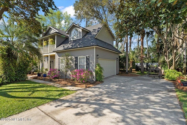 view of side of home with concrete driveway, roof with shingles, a lawn, a garage, and a balcony