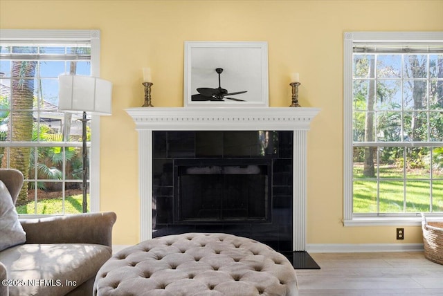 interior details featuring a tile fireplace, baseboards, and a ceiling fan