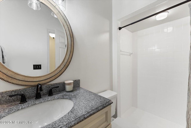 bathroom featuring vanity, toilet, and a tile shower