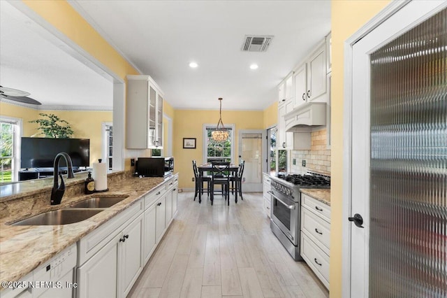 kitchen with visible vents, custom range hood, a sink, high end stainless steel range oven, and tasteful backsplash