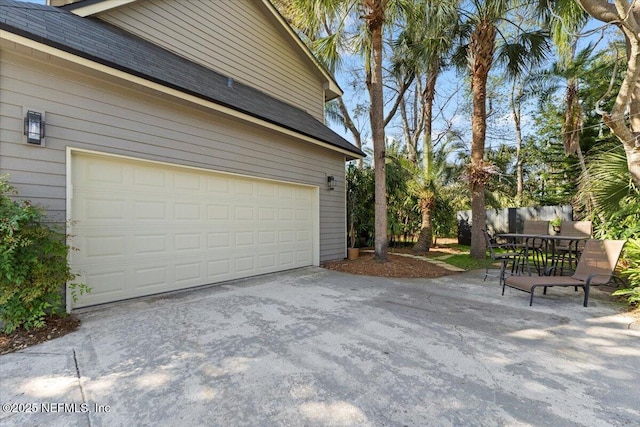 garage featuring driveway and fence