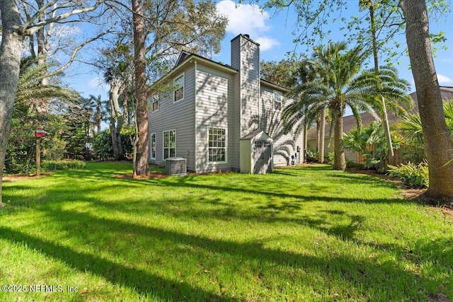 back of property with a yard, cooling unit, and a chimney