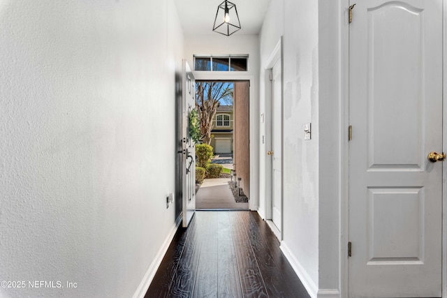 hallway featuring baseboards and dark wood-style flooring