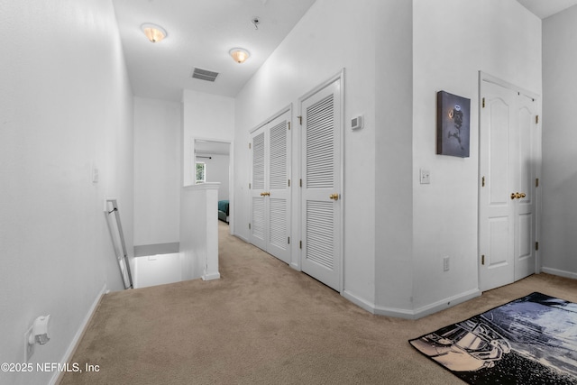 hallway featuring carpet, an upstairs landing, visible vents, and baseboards