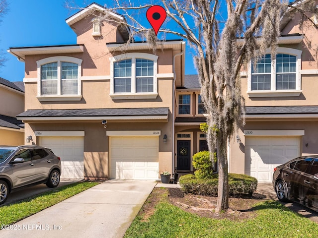 multi unit property with stucco siding, an attached garage, and driveway