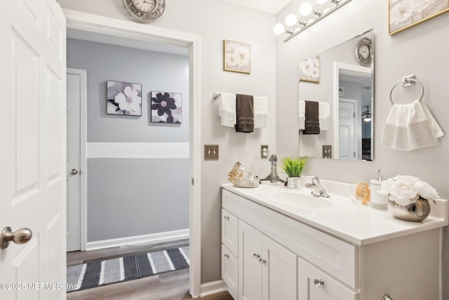 bathroom with vanity, wood finished floors, and baseboards