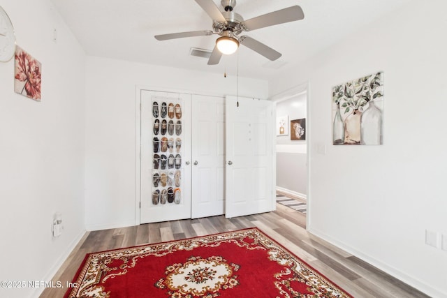 interior space with visible vents, wood finished floors, baseboards, and ceiling fan