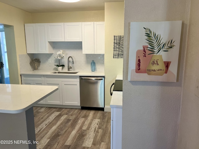 kitchen featuring a sink, stainless steel dishwasher, wood finished floors, white cabinets, and light countertops