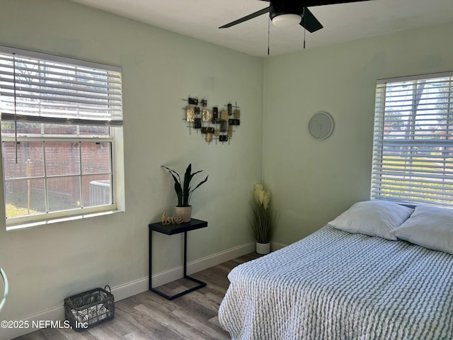 bedroom featuring baseboards, wood finished floors, and a ceiling fan