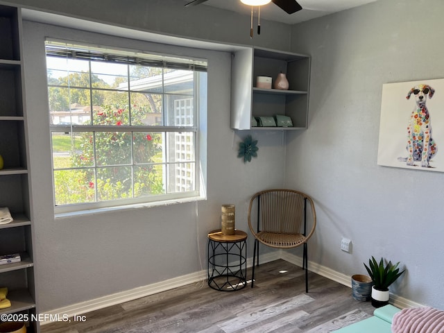 living area featuring ceiling fan, wood finished floors, baseboards, and a healthy amount of sunlight