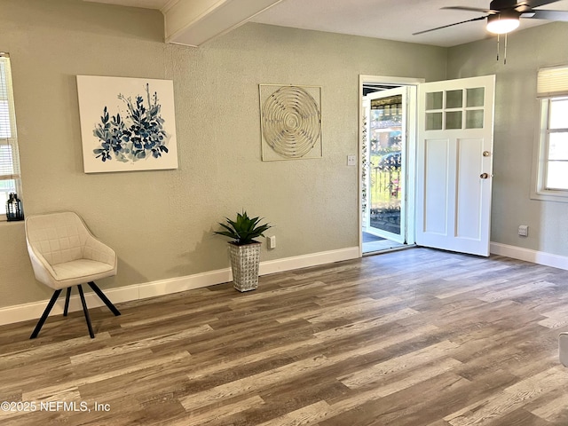 foyer entrance with baseboards, wood finished floors, a ceiling fan, and a textured wall