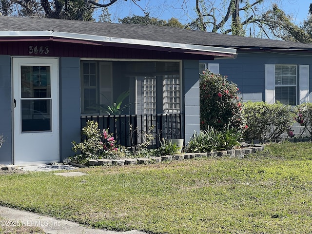 view of exterior entry featuring a lawn