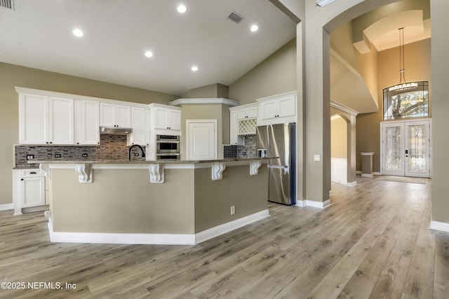 kitchen with a kitchen breakfast bar, arched walkways, appliances with stainless steel finishes, and visible vents