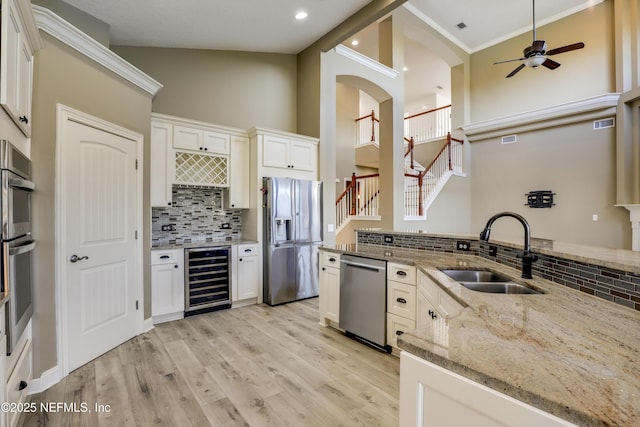 kitchen with beverage cooler, a ceiling fan, light wood-style flooring, a sink, and stainless steel appliances