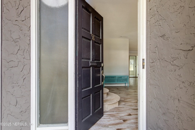 hall featuring wood finished floors and a textured wall