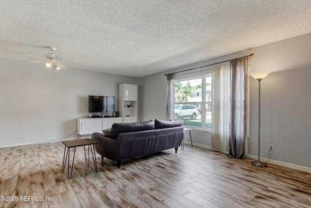 living area featuring baseboards, a textured ceiling, a ceiling fan, and wood finished floors