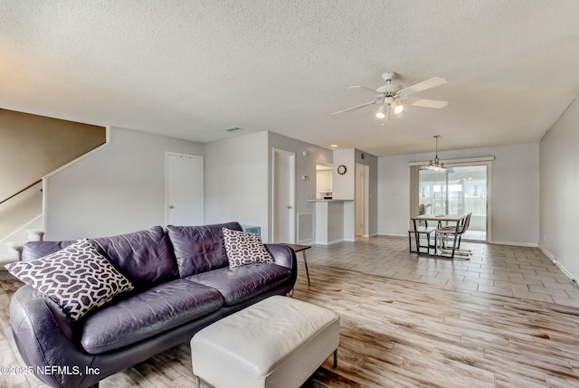 living room with stairs, ceiling fan, wood finished floors, and a textured ceiling