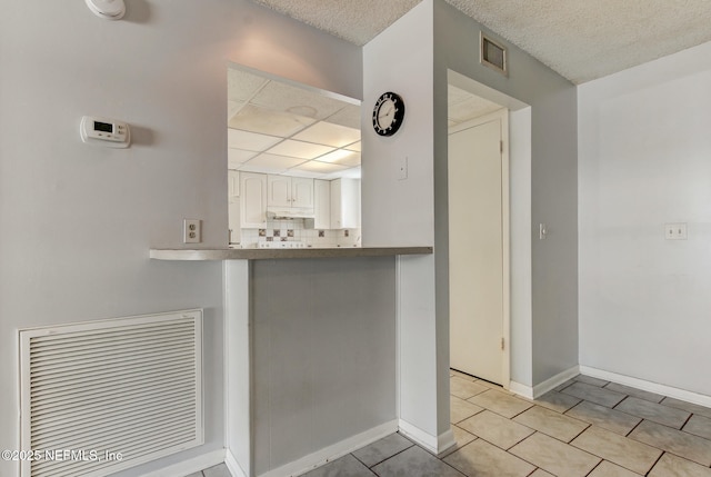 kitchen with tasteful backsplash, visible vents, baseboards, light tile patterned floors, and white cabinetry