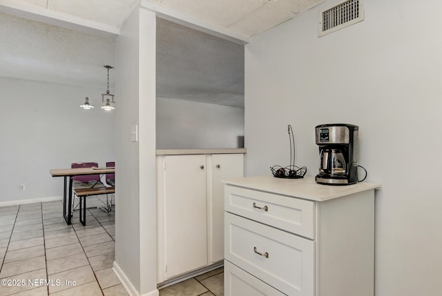 kitchen with visible vents, white cabinetry, light countertops, light tile patterned floors, and baseboards