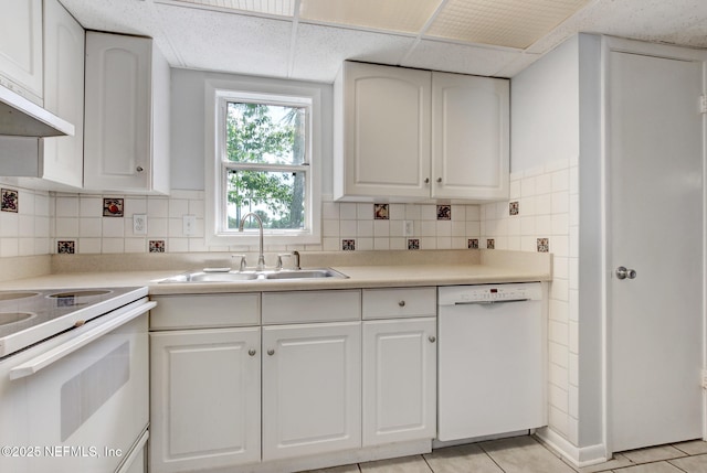 kitchen with white appliances, white cabinets, backsplash, and a sink