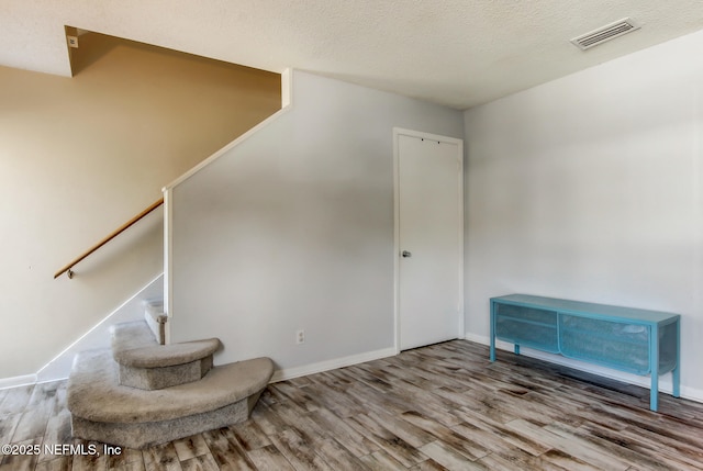 sitting room featuring visible vents, baseboards, stairs, wood finished floors, and a textured ceiling