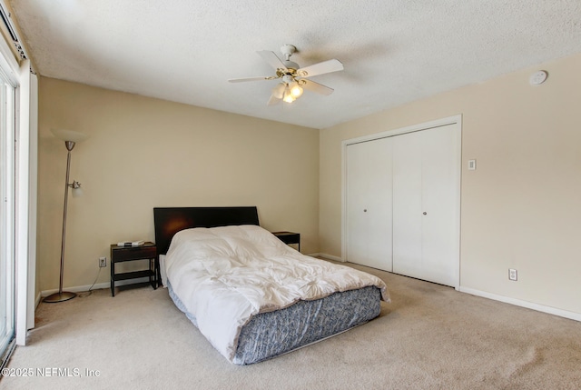 bedroom featuring a textured ceiling, a closet, carpet flooring, baseboards, and ceiling fan