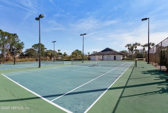 view of tennis court featuring community basketball court and fence