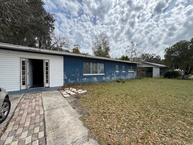 ranch-style house featuring concrete block siding and a front yard