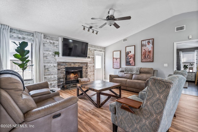 living area with lofted ceiling, light wood-style floors, visible vents, and a textured ceiling