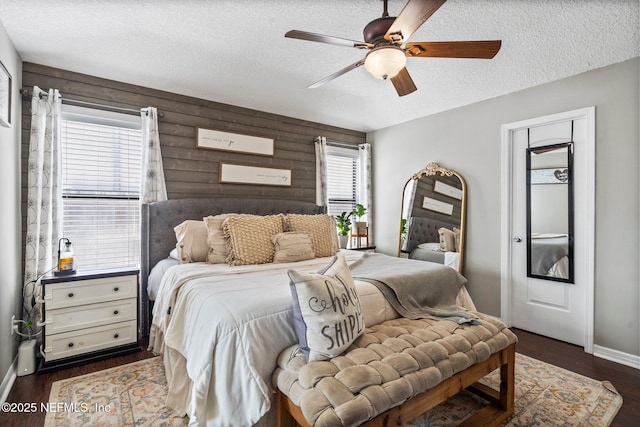 bedroom featuring baseboards, a textured ceiling, dark wood finished floors, and a ceiling fan