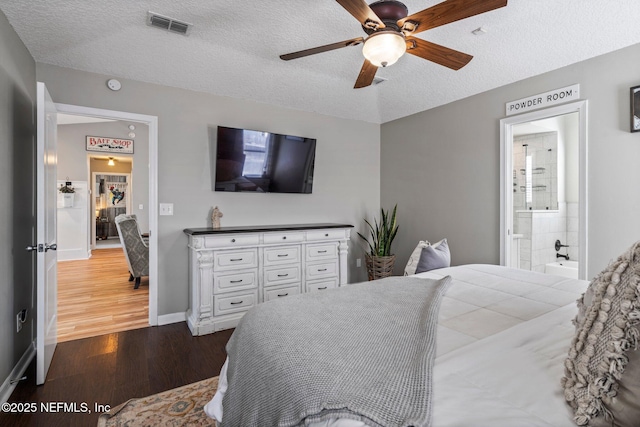 bedroom with visible vents, a textured ceiling, connected bathroom, baseboards, and dark wood-style flooring