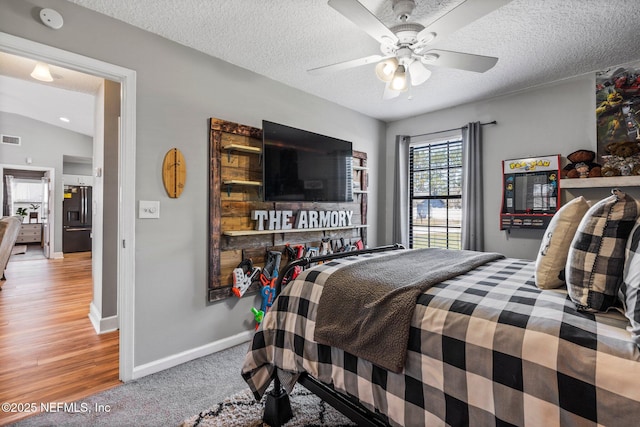 carpeted bedroom featuring visible vents, black fridge, a ceiling fan, a textured ceiling, and baseboards