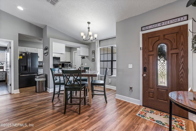 dining space featuring visible vents, dark wood-type flooring, baseboards, vaulted ceiling, and a notable chandelier