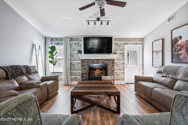 living area featuring visible vents, a textured ceiling, wood finished floors, and a fireplace