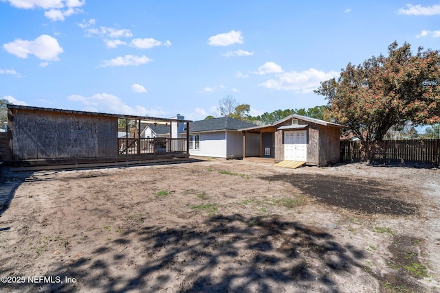 rear view of house with a deck, a storage shed, an outdoor structure, and fence