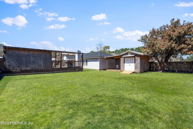 view of yard featuring a storage unit, an outbuilding, a wooden deck, and fence