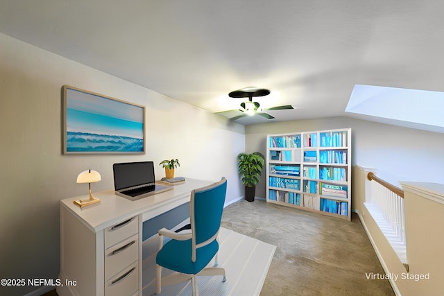 office featuring a ceiling fan, a skylight, carpet, and baseboards