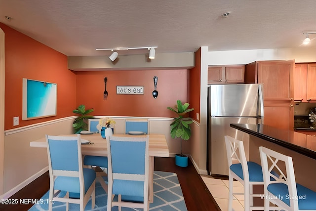 dining area with rail lighting, baseboards, and a textured ceiling