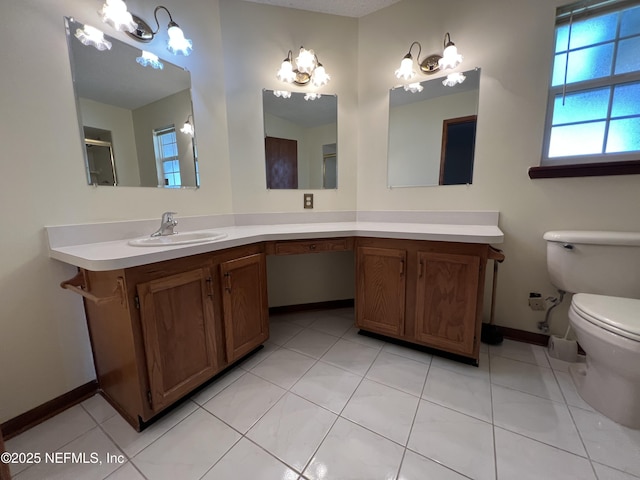 bathroom with vanity, baseboards, toilet, tile patterned floors, and a notable chandelier