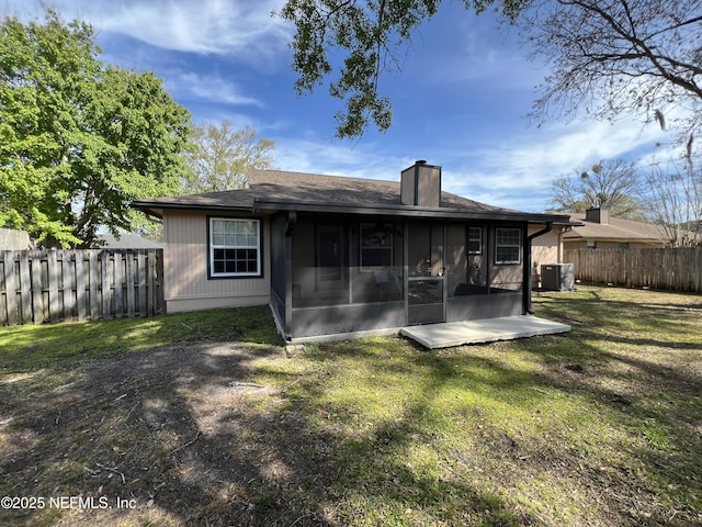 back of property featuring central AC, fence, a yard, a sunroom, and a chimney