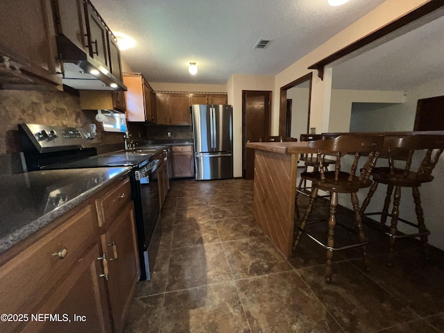 kitchen with visible vents, a sink, stainless steel appliances, under cabinet range hood, and dark countertops