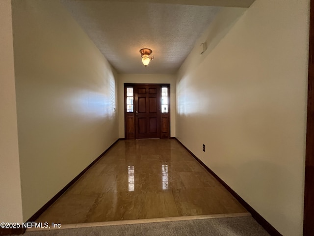 doorway to outside with baseboards and a textured ceiling